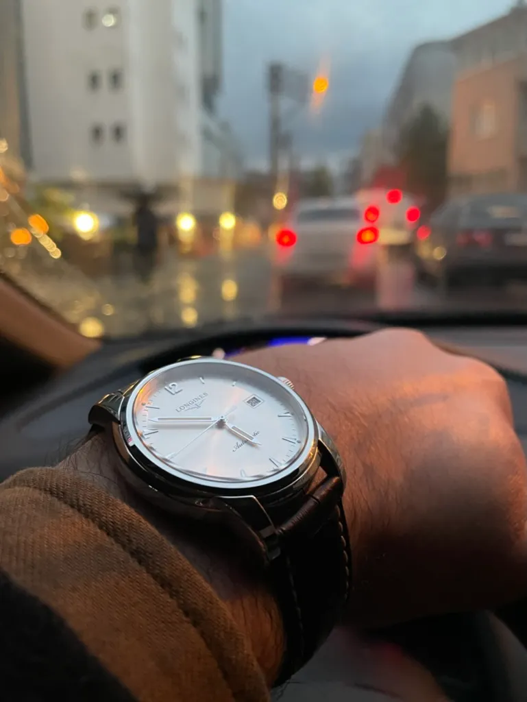 Yağmurlu akşam trafiğinde beyaz kadranlı Longines St. Imier